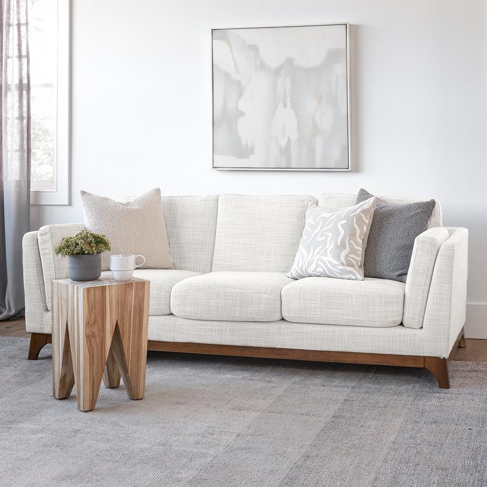 The Ceni Sofa on a gray rug with a wooden table in front of it.