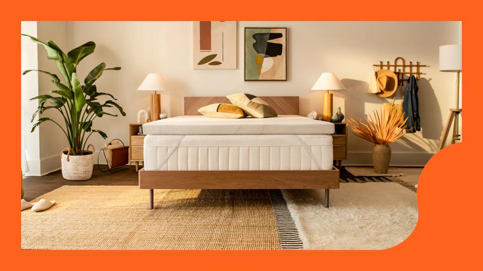 Tempur-Pedic mattress topper on a bed in a warm, neutral bedroom with an orange border.