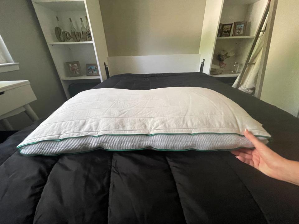 A woman's hand touching the Brooklinen Marlow Pillow on a bed.