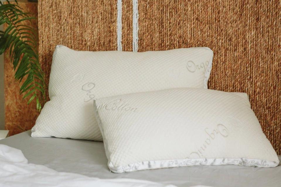 A pair of Nest Bedding Easy Breather Natural Pillows against a woven wall