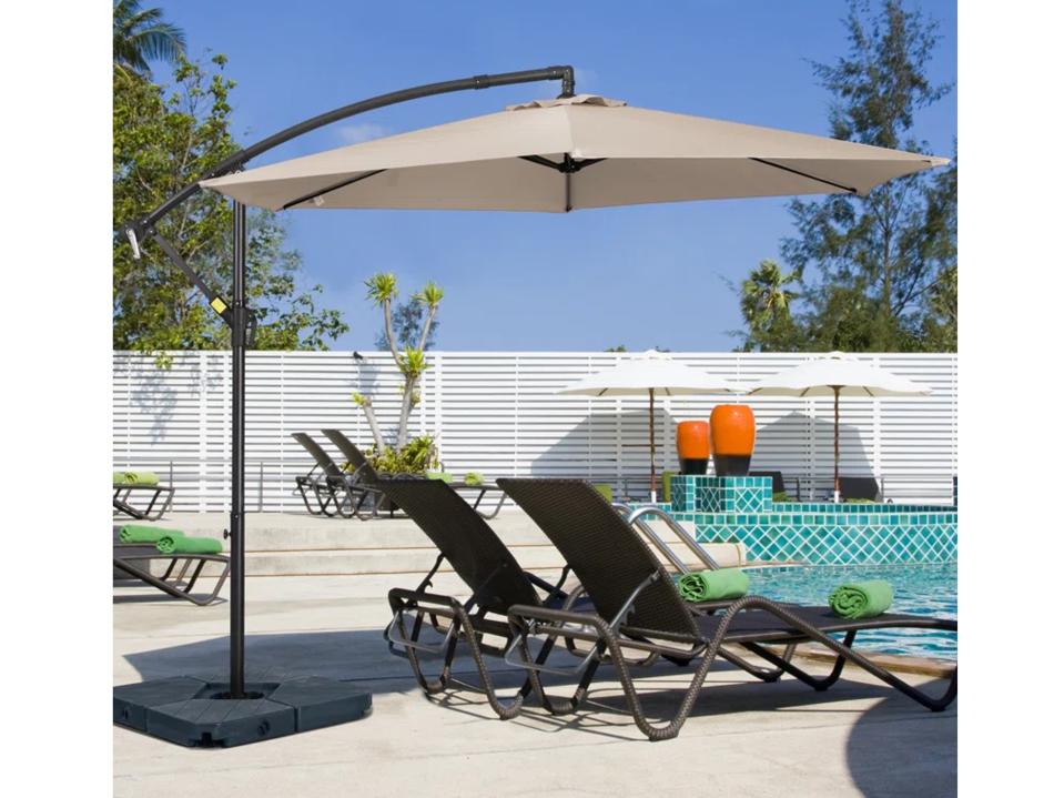 Arlmont & Co. Ersheen Cantilever Umbrella shades chaises by pool.