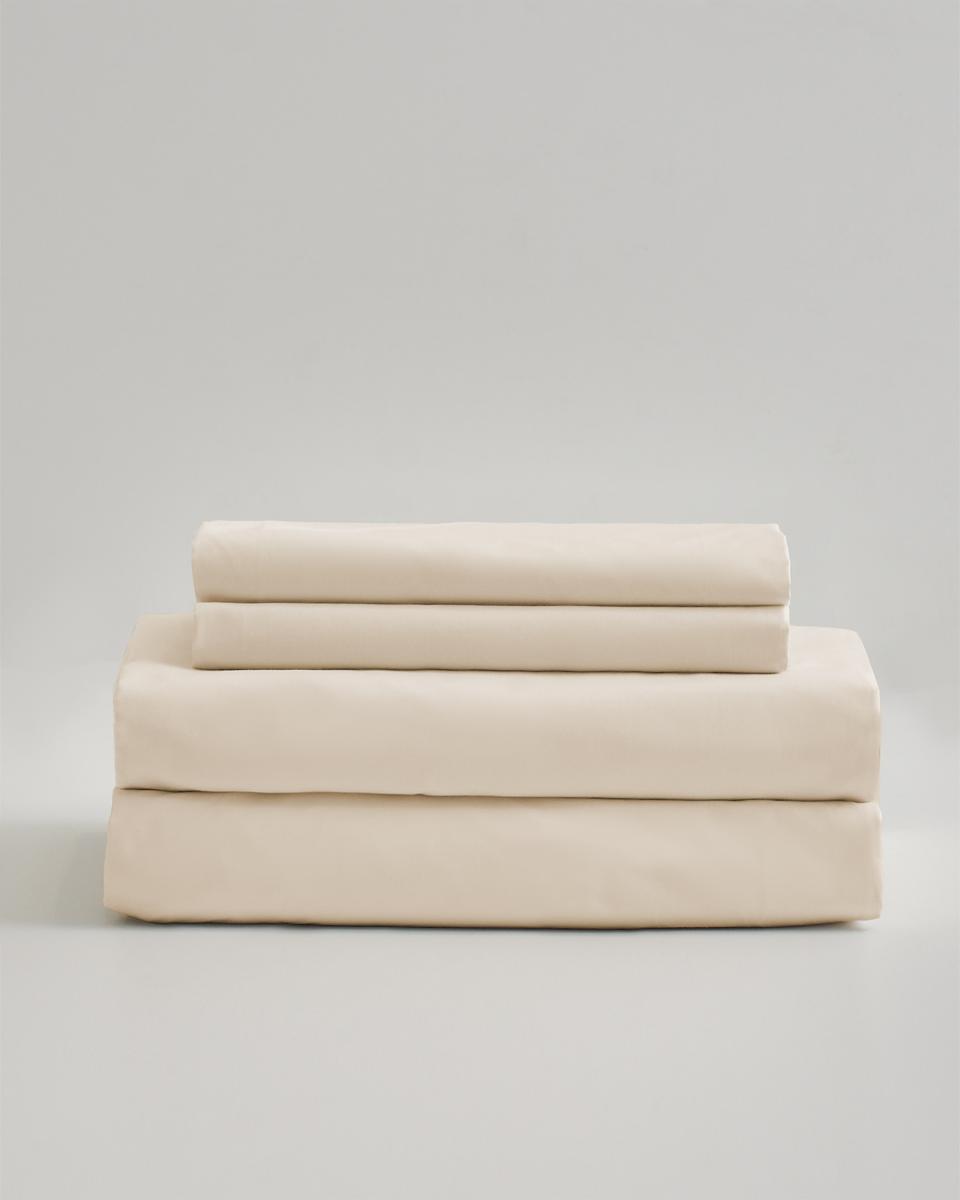 Classic Organic Percale Sheet Set in cream folded and stacked on top of each other. 