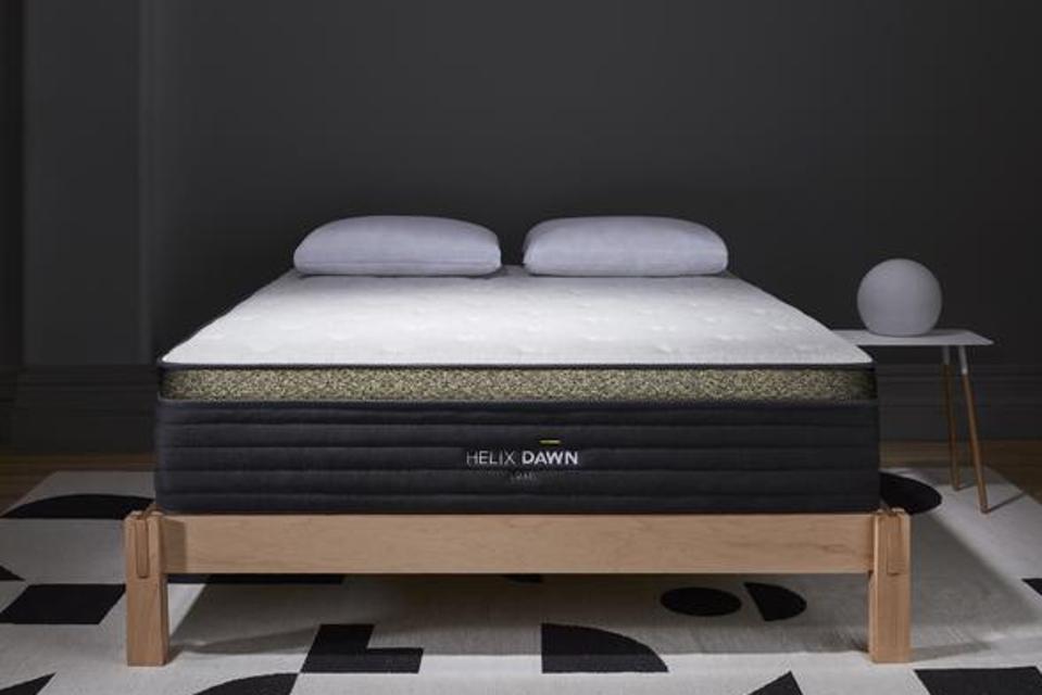 Helix Dawn LUXE mattress on a light wooden bed frame with a back and white rug underneath.