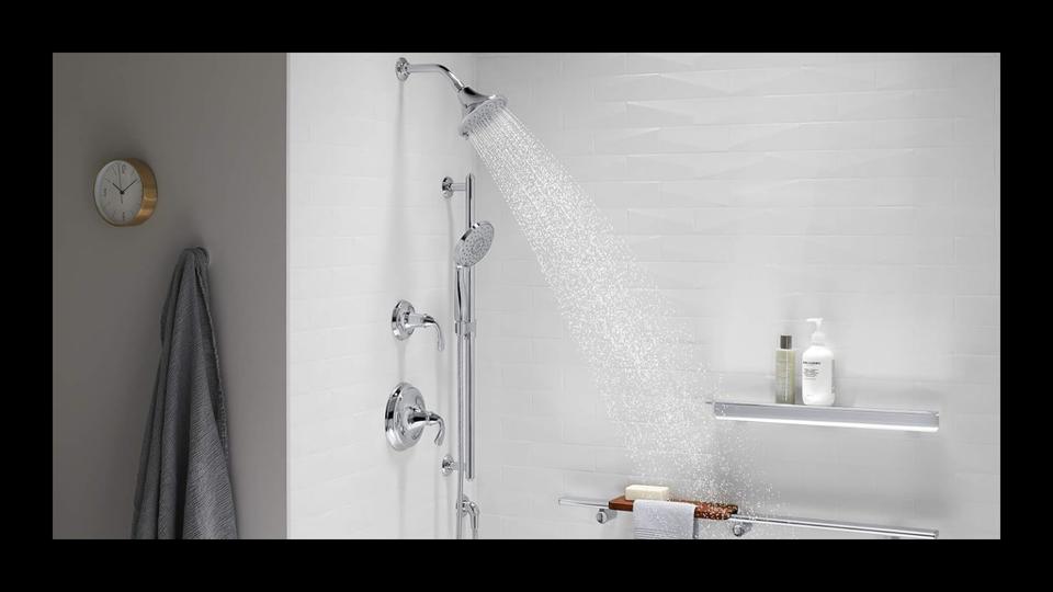 A white bathroom with the a silver shower streaming water