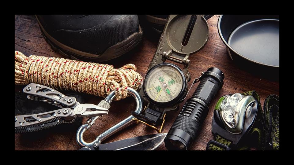 A compass, rope, flashlight and other tools as part of a bug out bag on a table