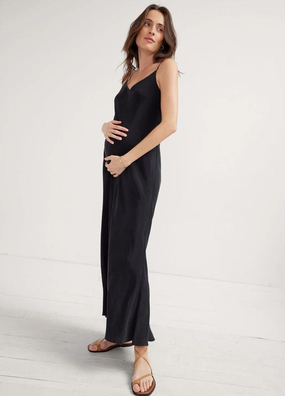 A pregnant woman wearing the Hatch The Ricky Slip Dress in black