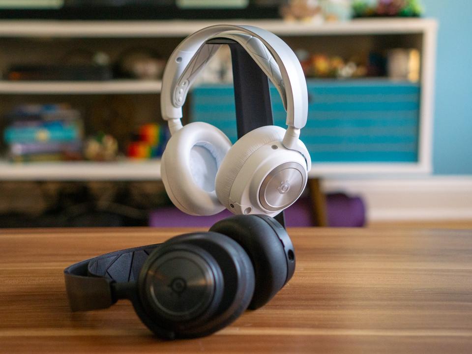 A pair of headsets, one black and the other white, on a tabletop.