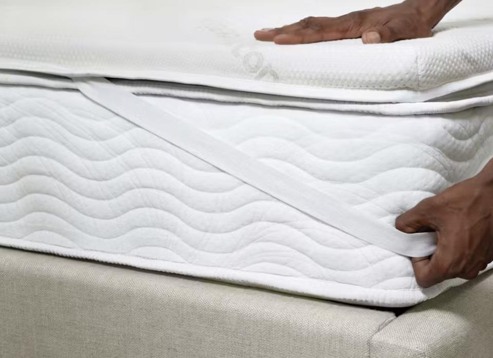 Hands pressing on the Saatva Graphite Memory Foam Mattress Topper