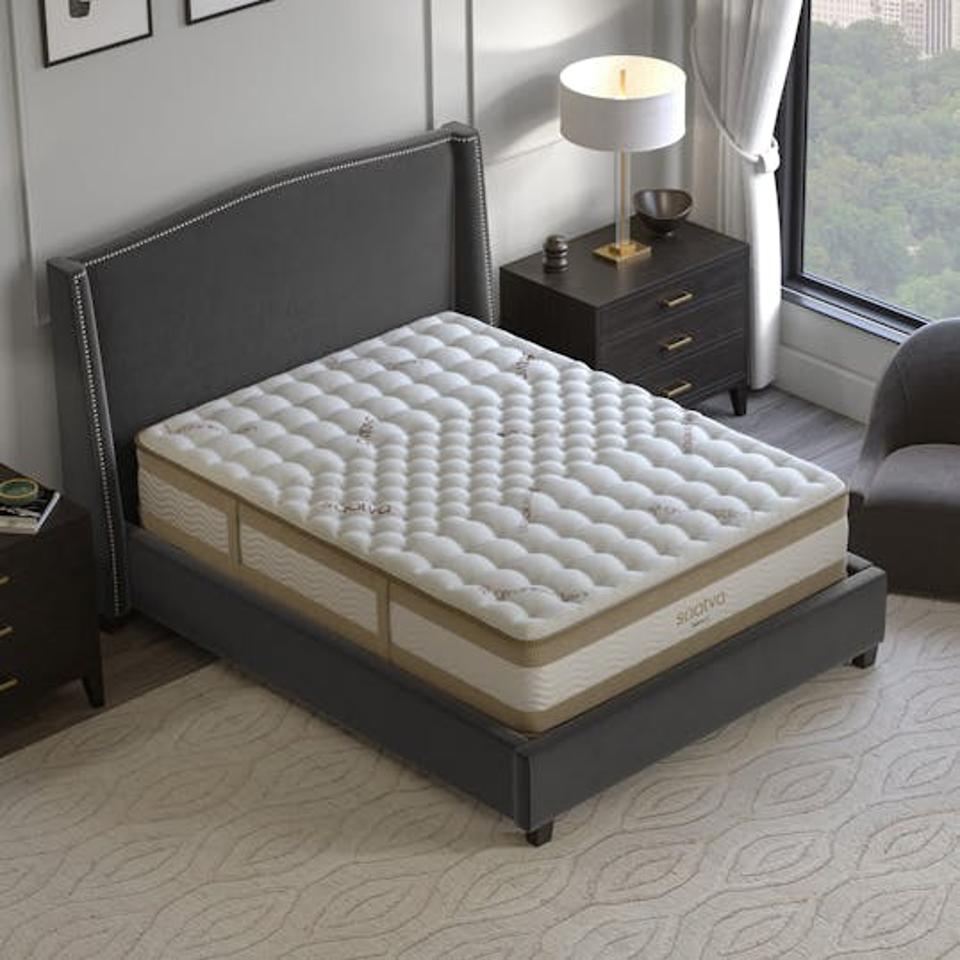 The Saatva Rx mattress on a dark grey bed frame with a headboard.