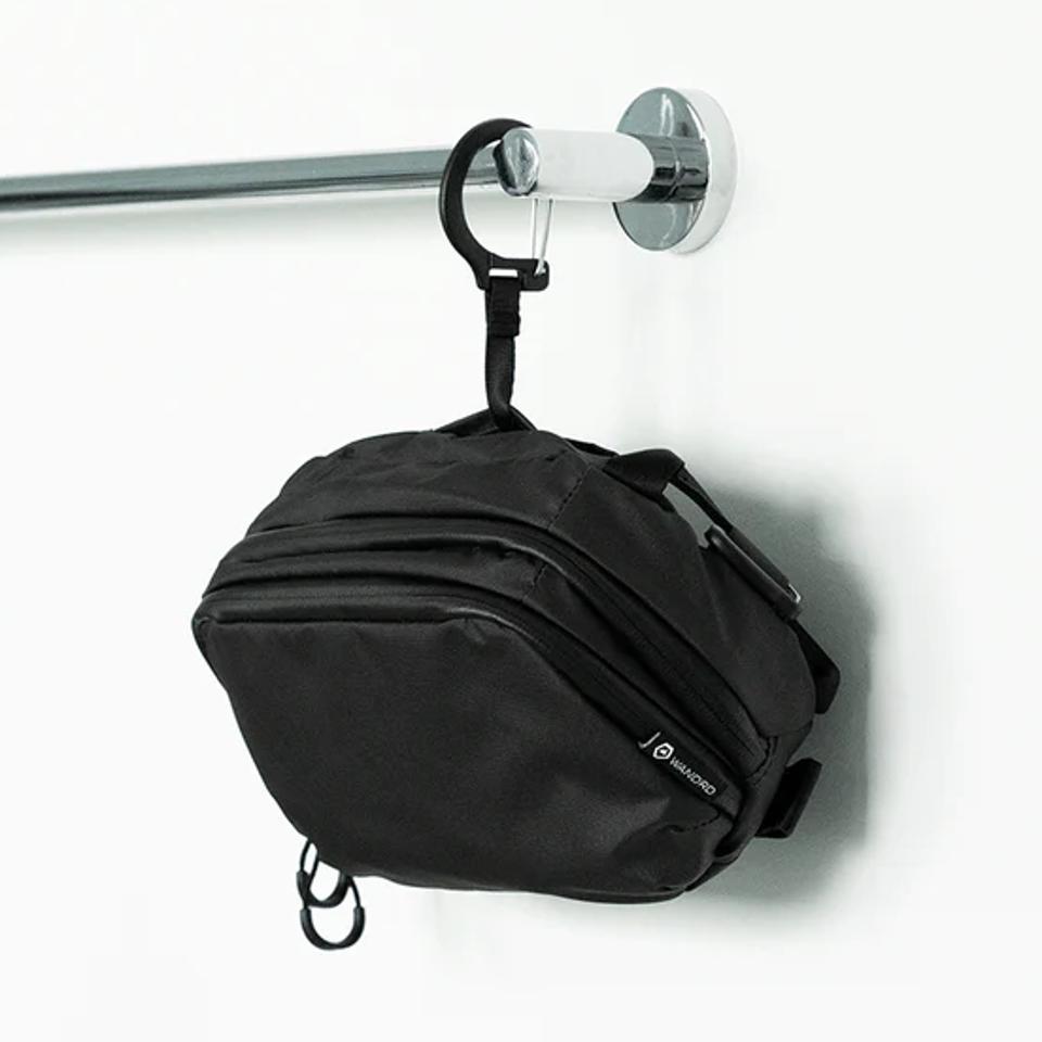 Wandrd Toiletry Bag hanging from railing against white wall