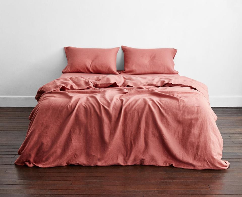 Bed Threads Pink Clay 100% French Flax Linen Bedding Set, lightly rumpled on a bed sitting on a wood floor