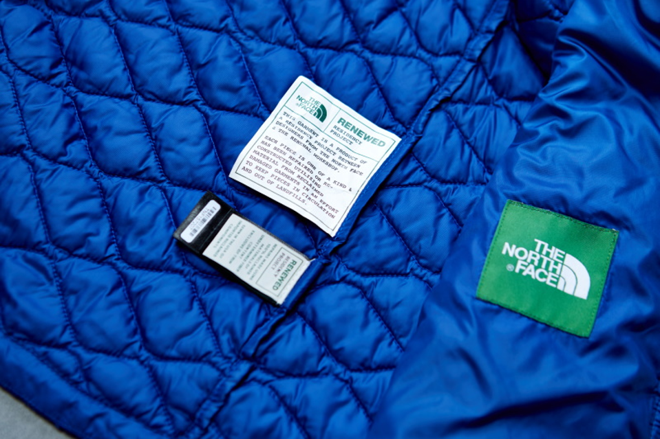 A blue The North Face jacket with a Renewed tag