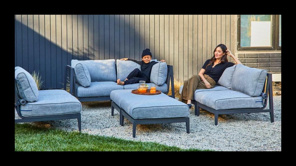 Photo of mom & son sitting on gray Outer aluminum 4-piece sofa set outside on gravel in day