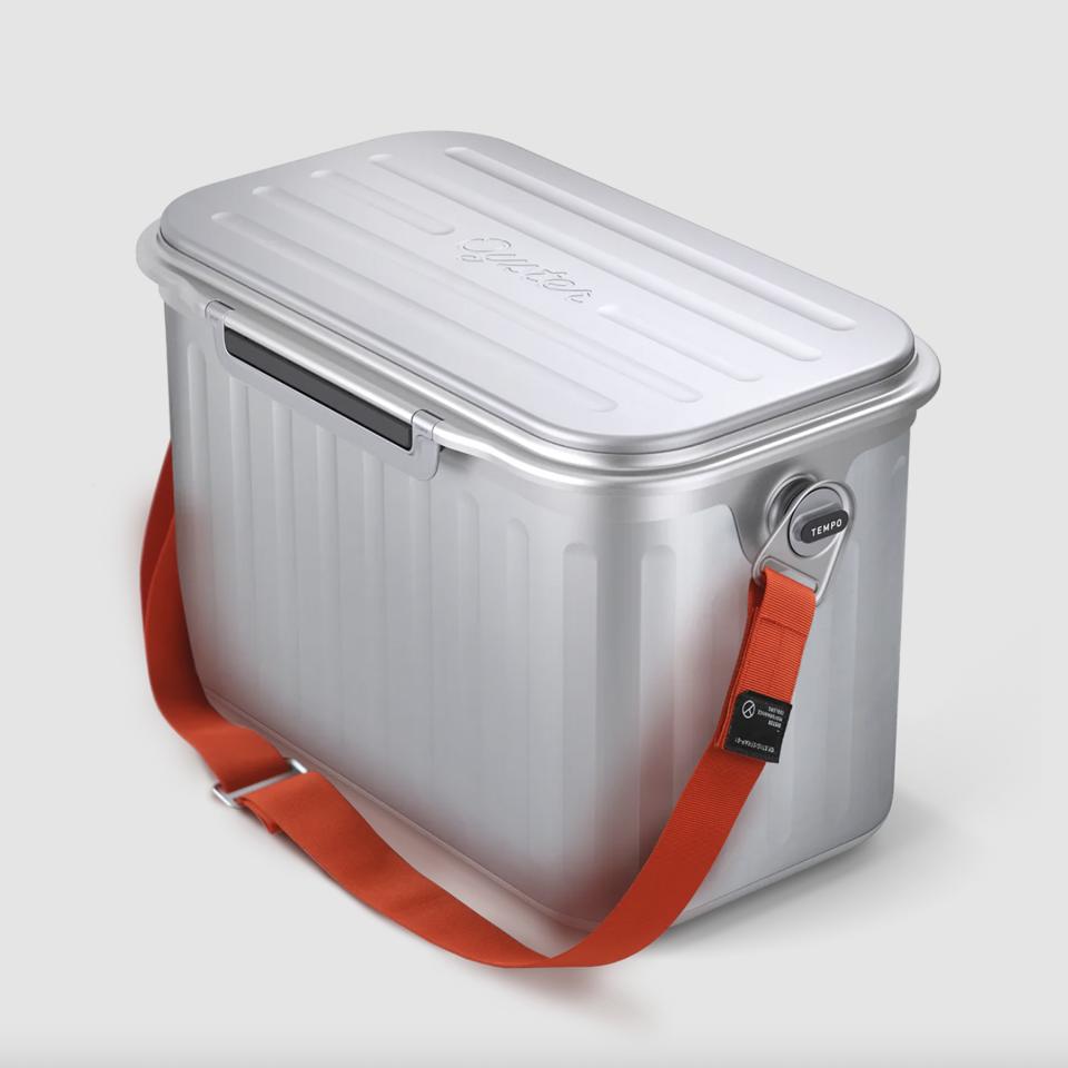 A silver cooler with a red strap on a grey background