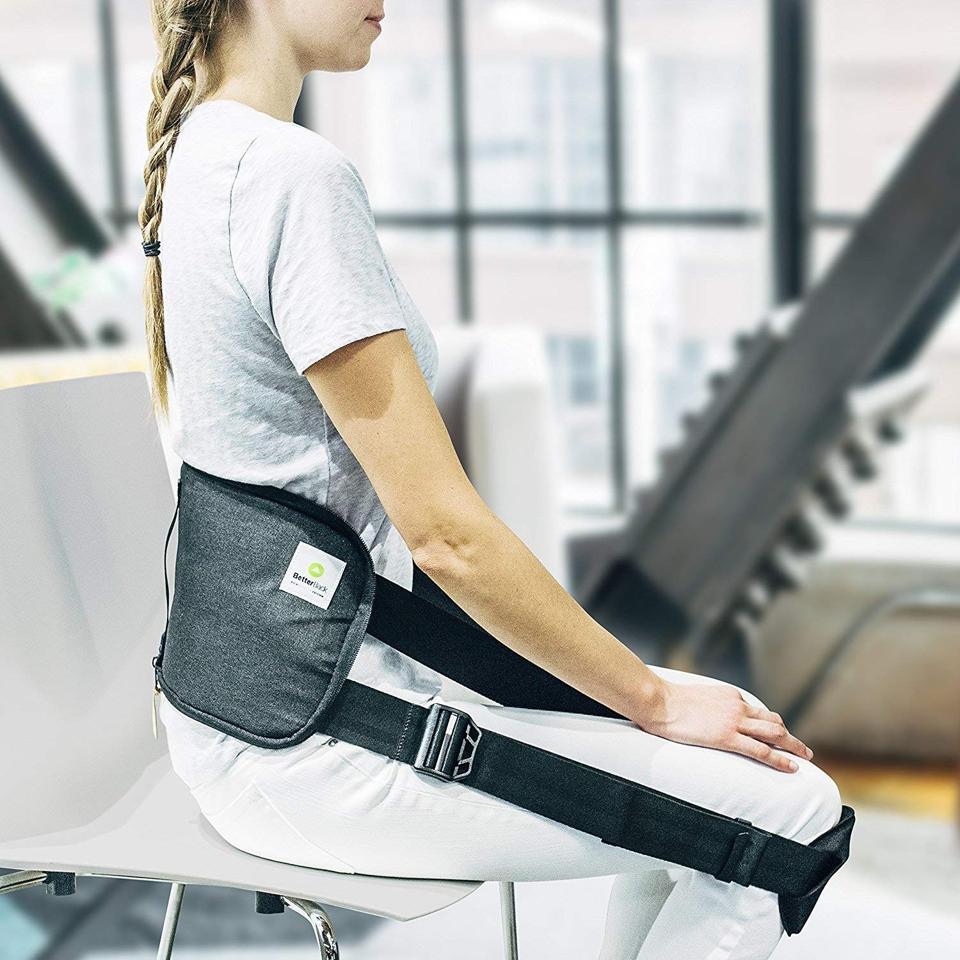 A woman sitting in a chair using the BetterBack Posture Corrector