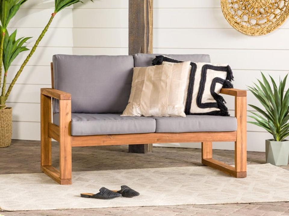 Lifestyle image of Red Barrel Studio Acacia Outdoor Loveseat with gray cushions on a patio