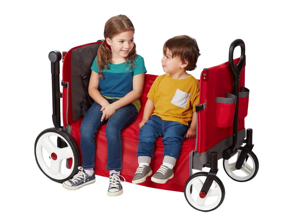 2 toddlers sitting on red Radio Flyer Convertible Stroll 'N Wagon on white background