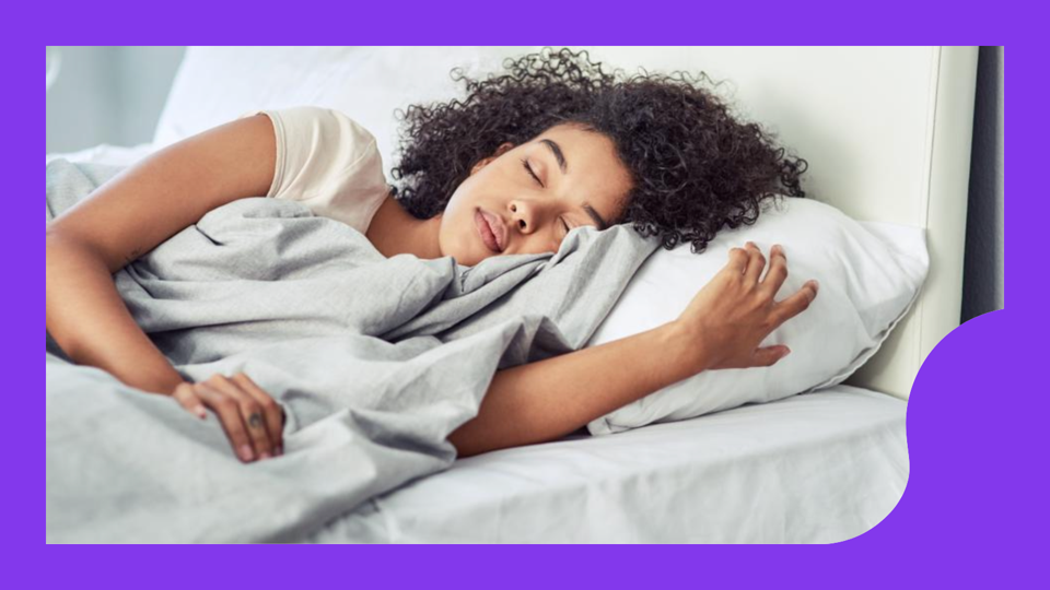 A person asleep on their side with a gray duvet and white sheets. 