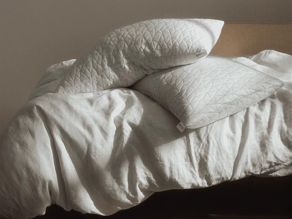 Two Coop Sleep Goods Original Adjustable Pillows on a bed.