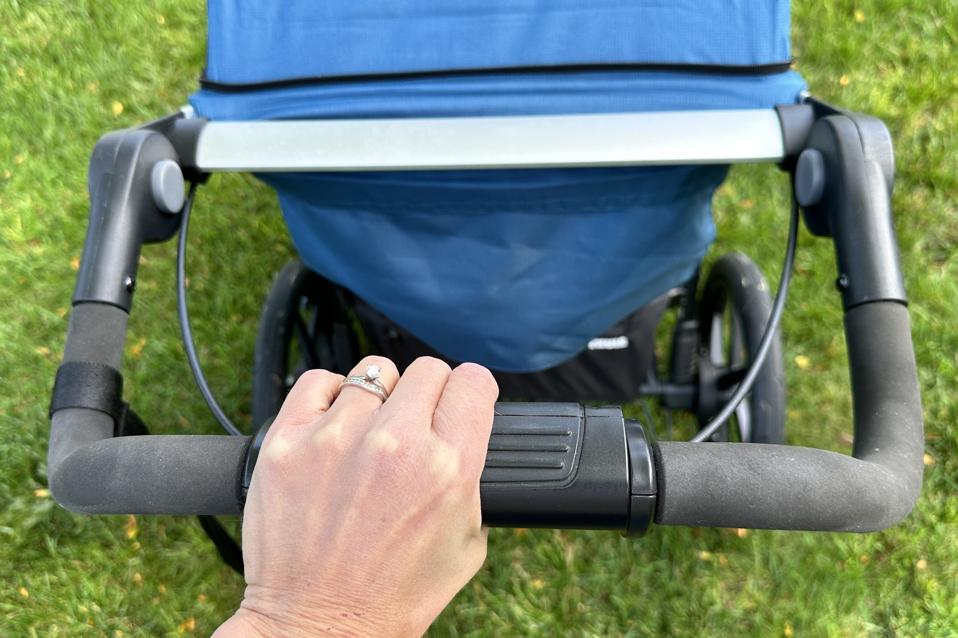 A close-up of the Thule Urban Glide 2 jogging stroller's handbrake with the author's hand.