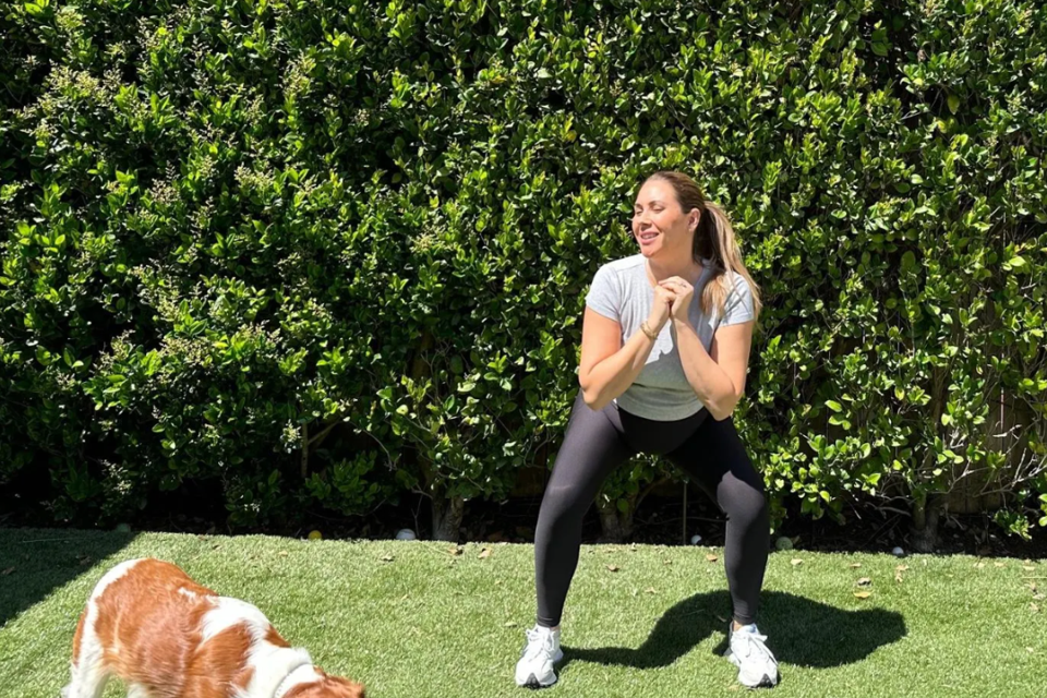 pregnant woman exercising outdoors wearing beyond yoga spacedye leggings w/ dog in daytime