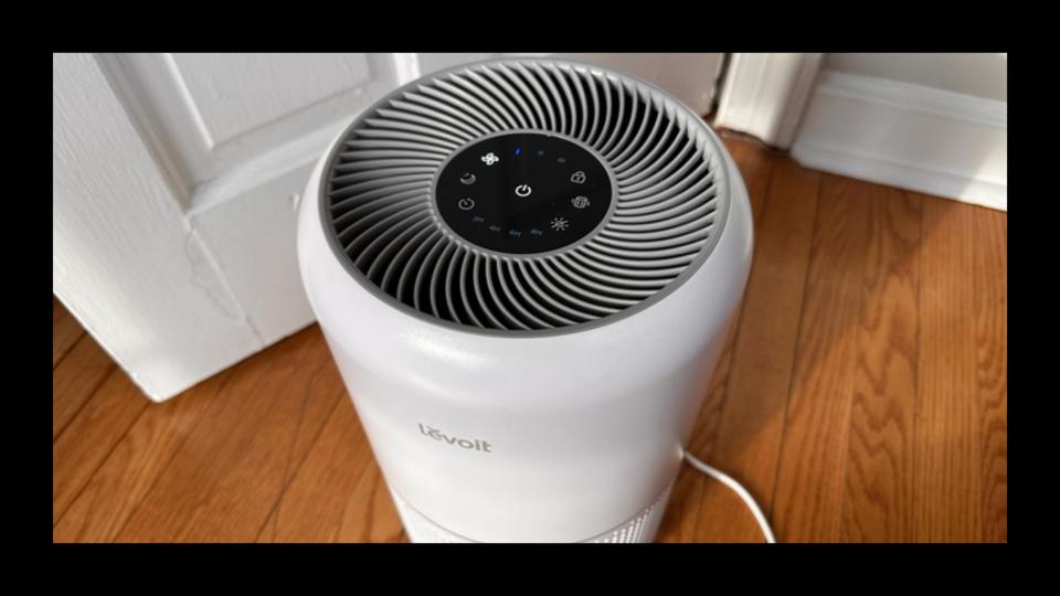 original photo of white levoit core 300 air purifier on wood floor next to bedroom door