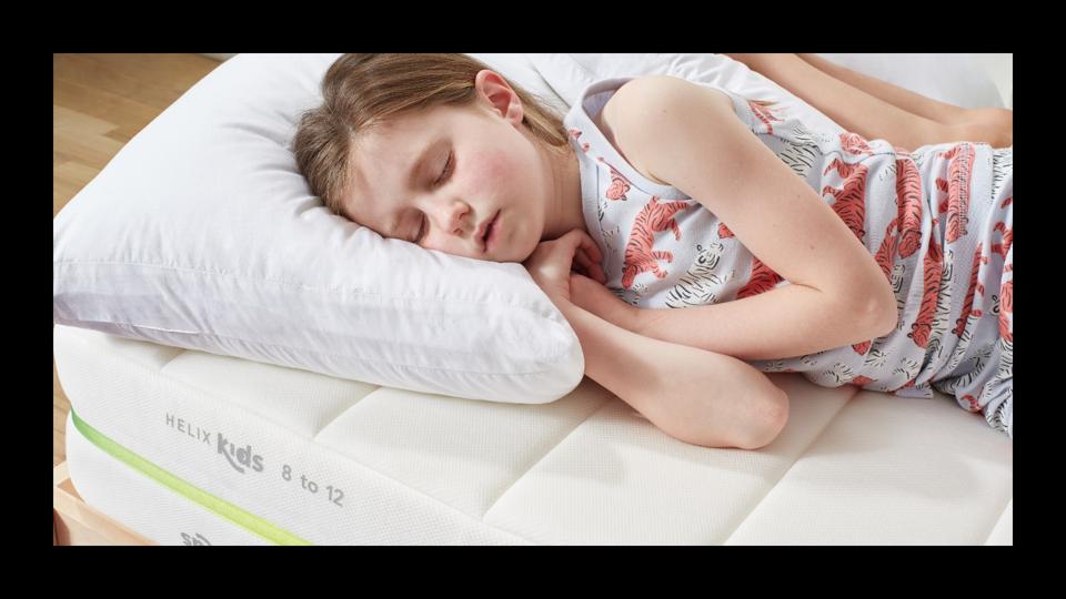 A young kid in tiger PJs lying on a Helix Kids mattress.