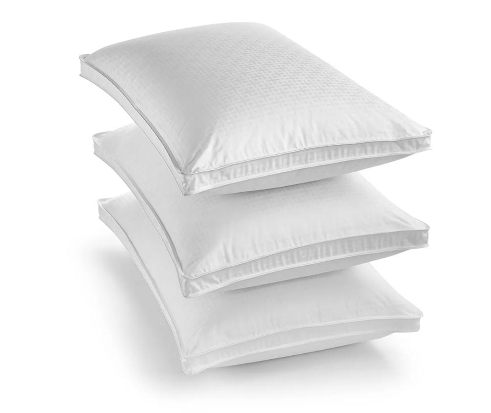 Three goose down pillows stacked in a pile on white background.