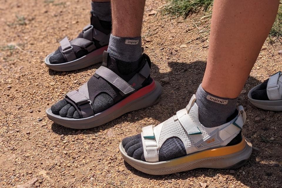 Two people wearing the Teva Aventrail sandals on a dirt path