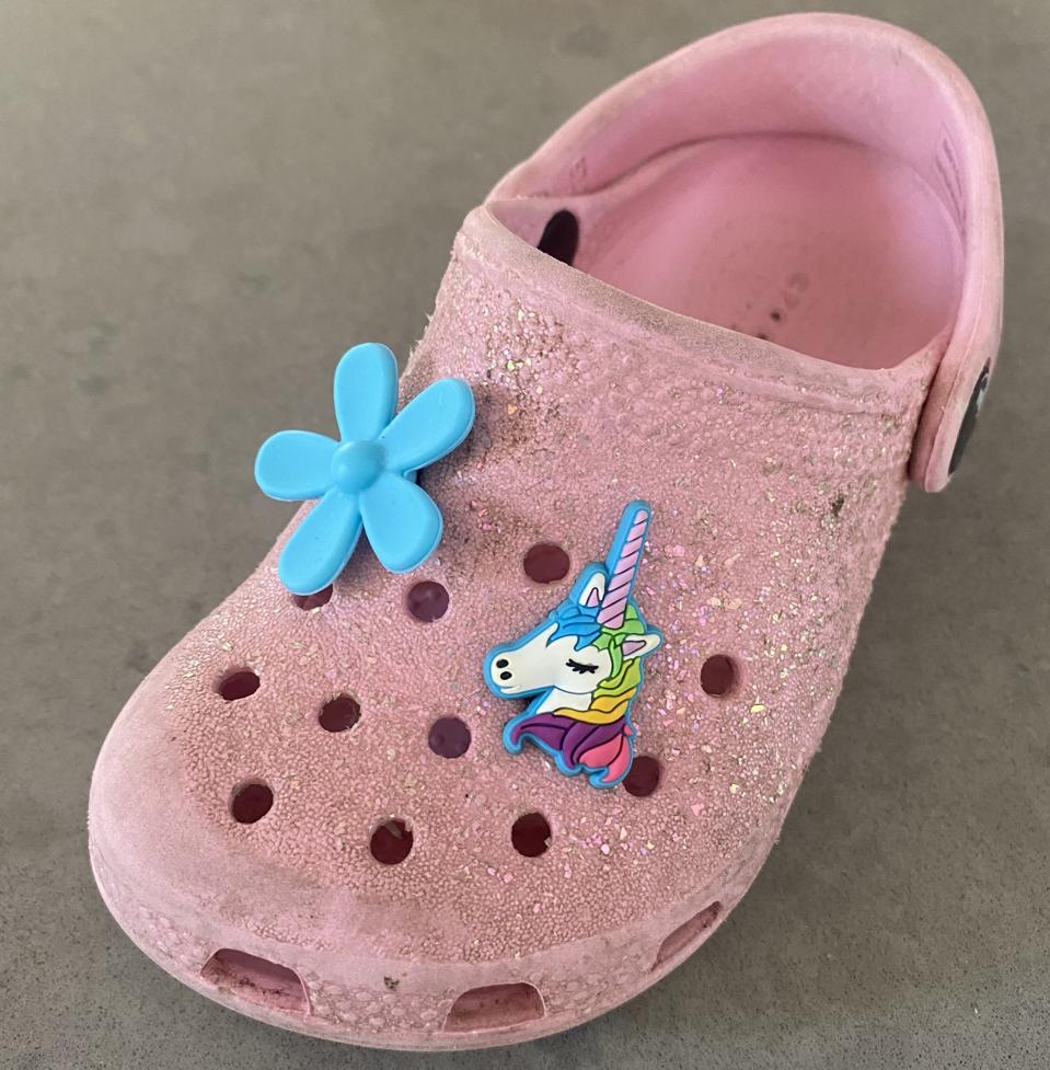 Flower and unicorn Jibbitz charms decorating a well-loved pink Croc