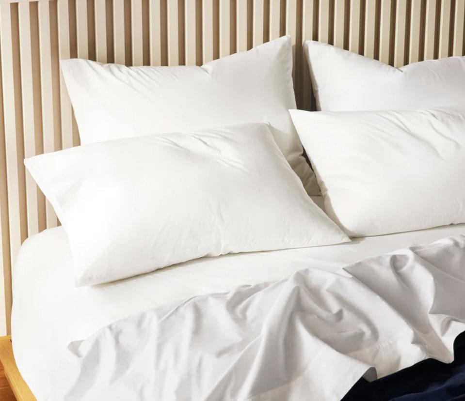 Brooklinen Classic Percale Sheets shown on a bed with pillows 