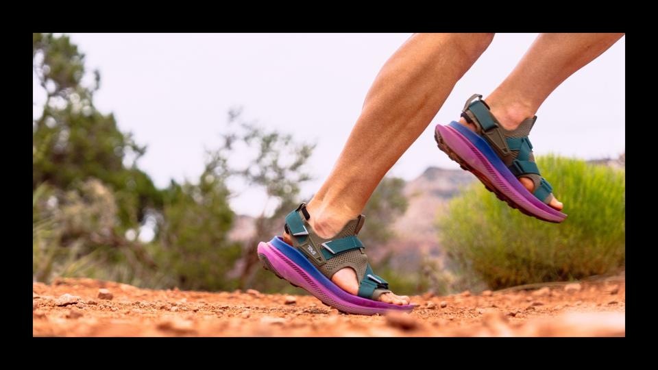 A person running in the Teva Aventrail sandals in the desert on dirt