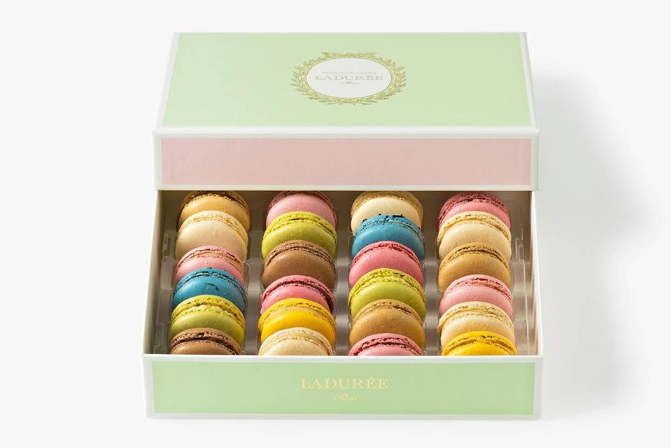 A pink box filled with Lauduree macarons in varying colors, like pink, green, yellow, and brown