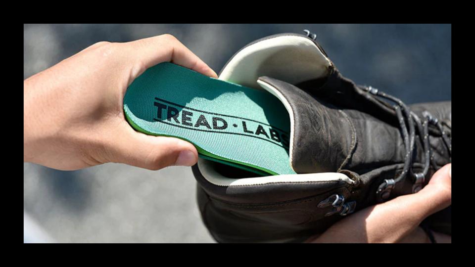 A person sliding a set of Tread labs insoles inside a hiking boot