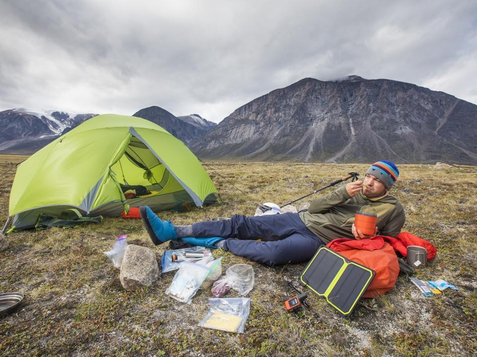 Climber eats meal, relaxes, charges devices at campsite.