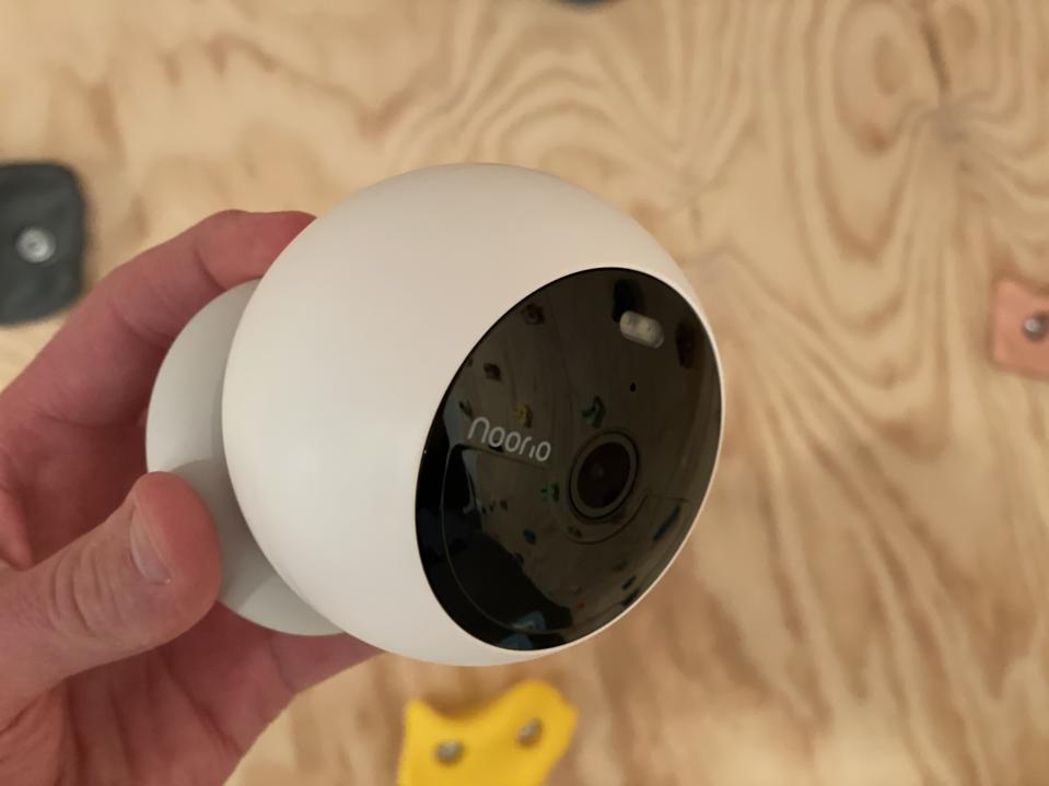 A side view of the Noorio B210 security camera with a plywood background