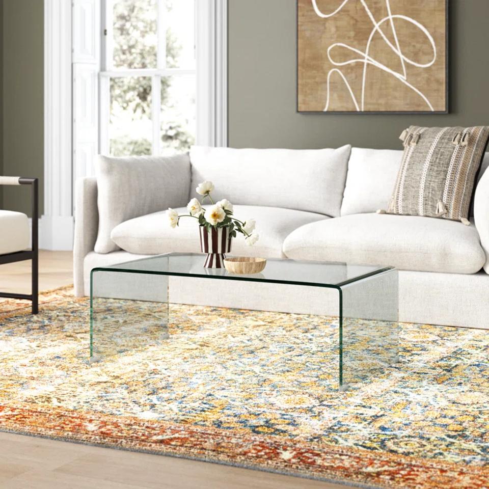 Ashlan Glass Coffee Table in a living room with a rug and white sofa.