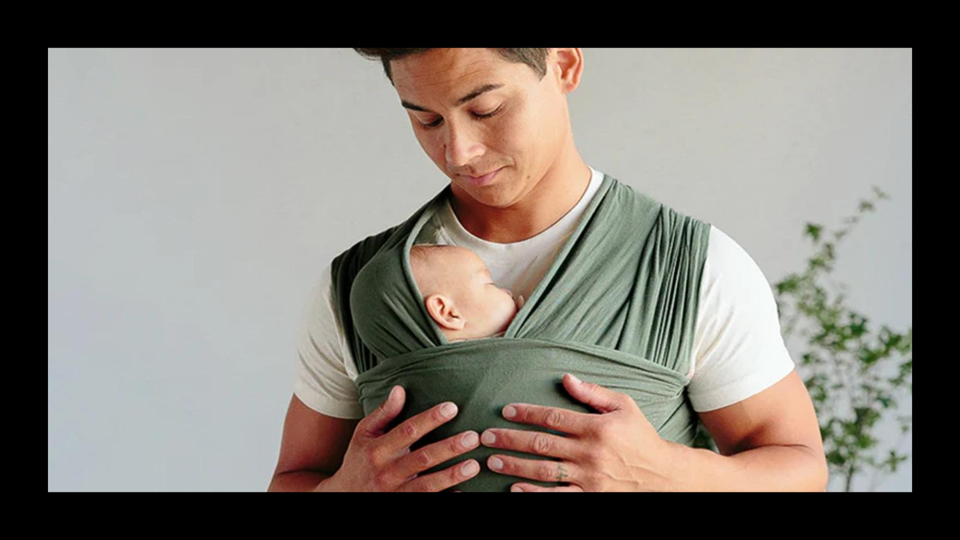 Man wearing a baby in with the Solly Baby wrap. 