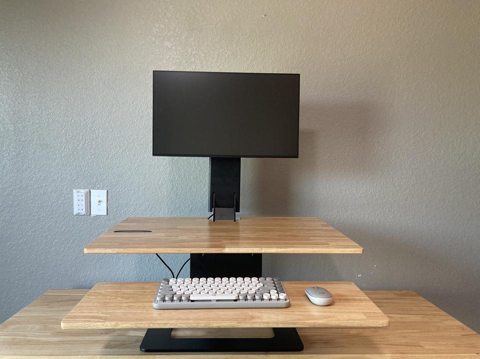 The Uplift E7 with a keyboard and monitor on it with a grey wall behind it