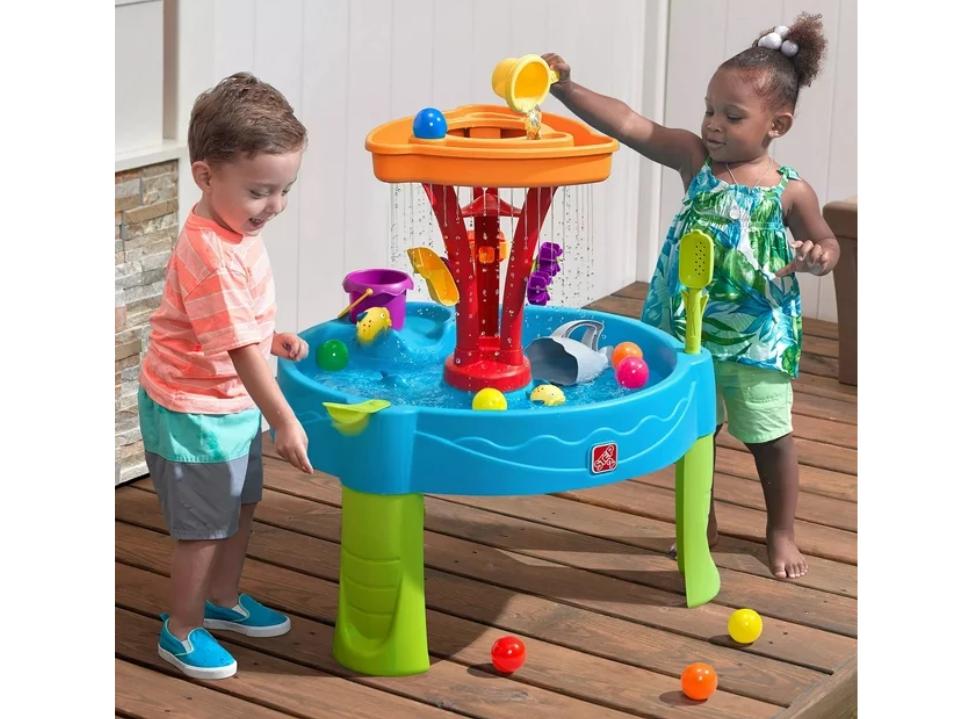 2 toddlers playing w/ Step2 Summer Showers Splash Tower Water Table outside on wood deck