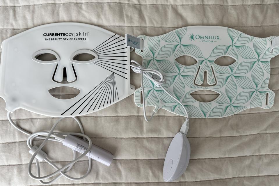 CurrentBody Skin LED Light Therapy Face Mask and Omnilux Contour Mask lying side by side