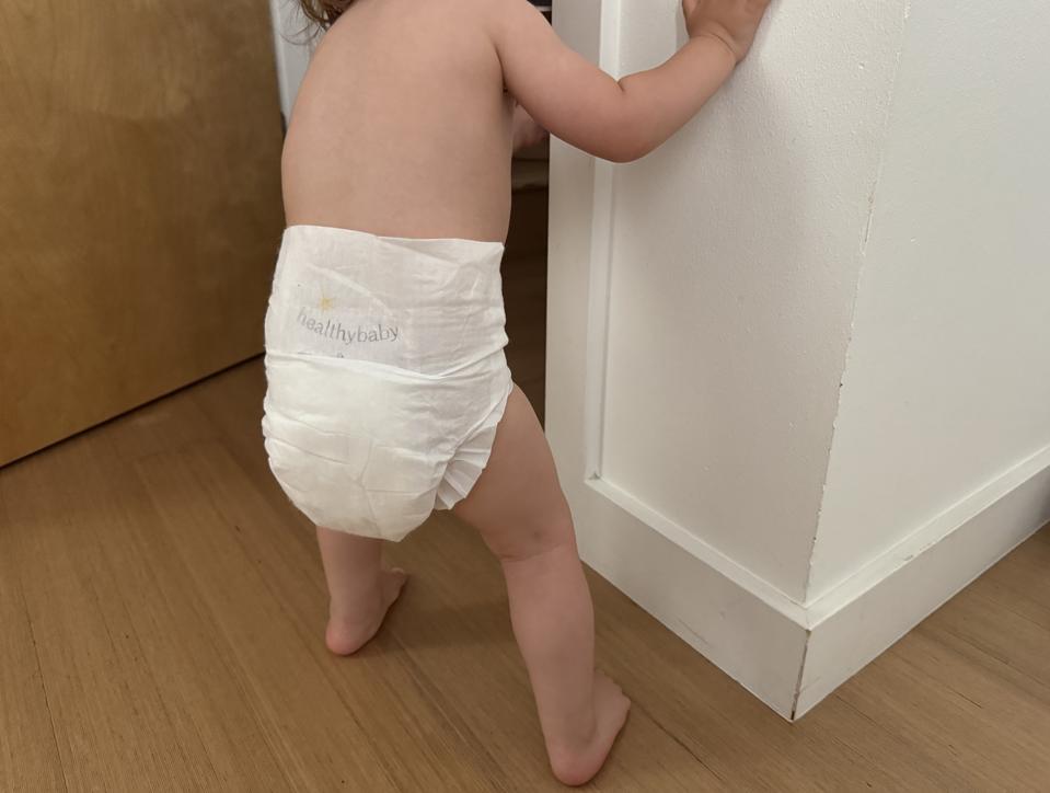 Toddler standing at a door, dressed in just a HealthyBaby diaper. 