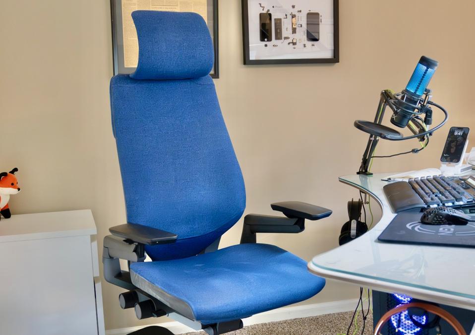 Blue Steelecase Gesture chair in front of desk in home office, beige wall in background.