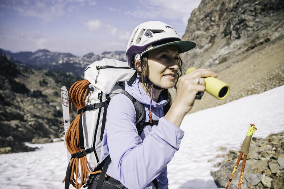 woman in a snowy alpine setting using a yellow monocular