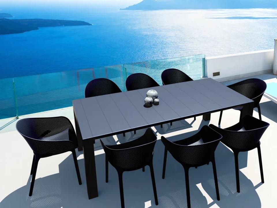 Lifestyle image of a black Allmodern Farrah Extendable Outdoor Dining Table by the ocean. 