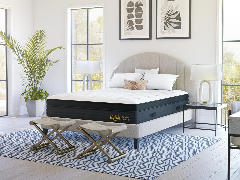 Nolah Evolution Comfort Plus Mattress on an upholstery frame in a bright, decorated bedroom.