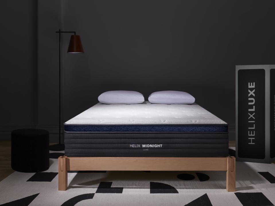 The Helix Midnight Luxe on a platform bed frame in a dark, black room.