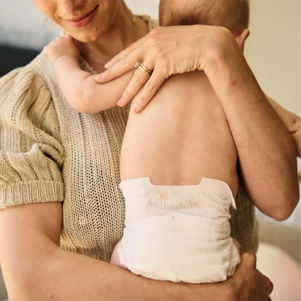 Mom holding a baby, who wears a white HealthyBaby diaper