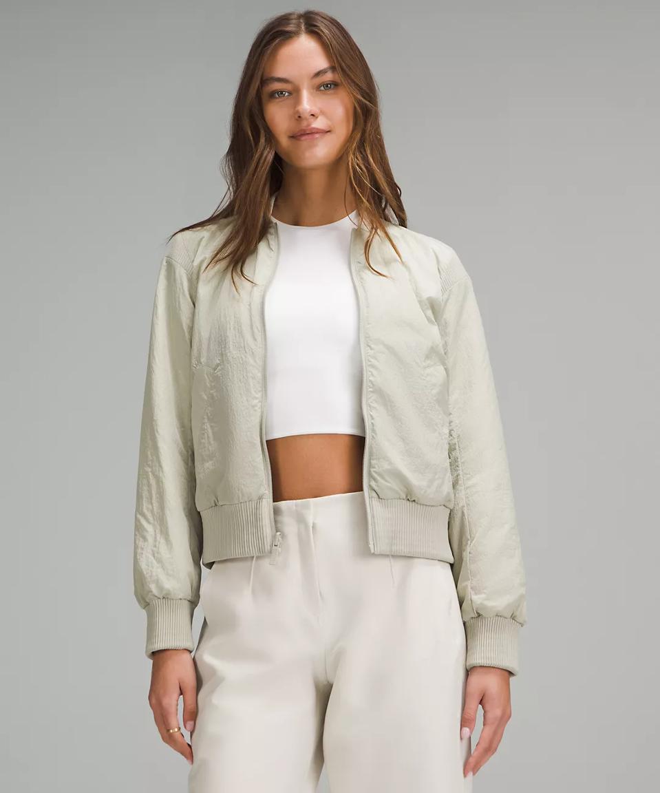 Woman wearing Lululemon Women's Reversible Insulated Bomber Jacket in Raw Linen/Bone