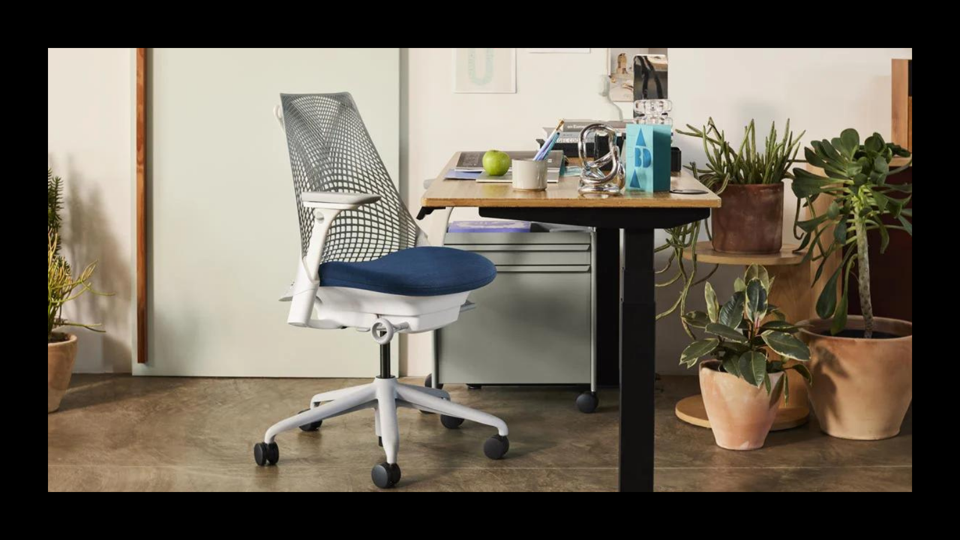 An organized desk in a WFH space featured with houseplants and a Herman Miller chair. 